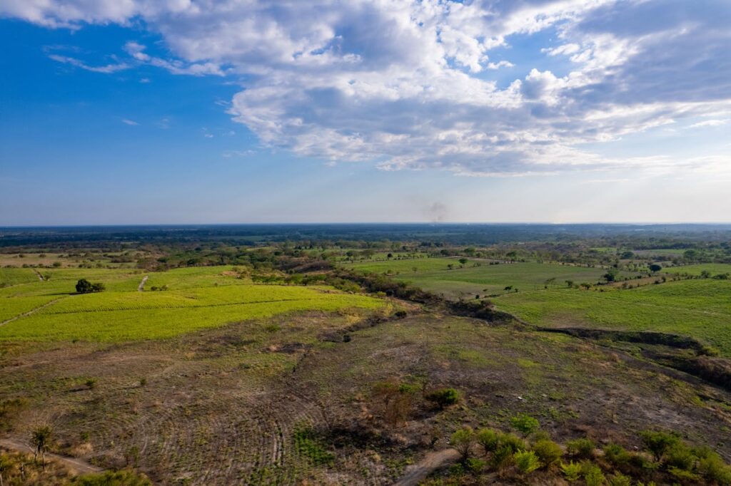 Stunning aerial shot of a vast landscape in El Salvador capturing fields and greenery under a blue sky.